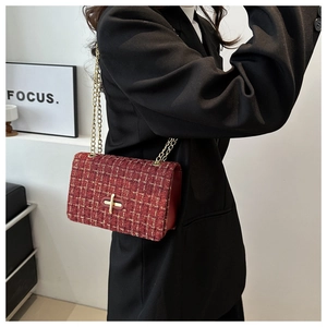 Détail du sac bandoulière en tweed rouge avec chaîne dorée et fermoir rotatif chic