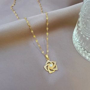 Macro detail of gold flower pendant with central pearl and micro-pave zirconia crystals