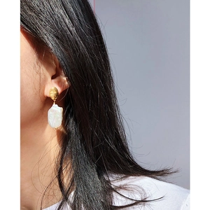Close-up of vintage baroque pearl earrings with hammered gold finish on female model