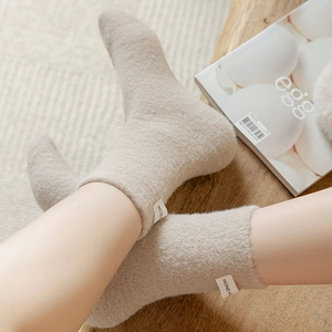 Detail of warm beige plush socks on feet, soft thermal winter socks for home comfort