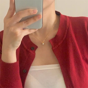Elegant gold bow pearl necklace worn with a stylish red cardigan in a mirror selfie