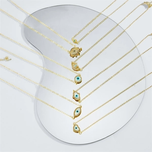 Golden Hamsa and Evil Eye necklaces with mother of pearl and zircon charms on mirror