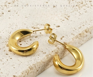 Close-up of polished 18K gold-plated C-shape stainless steel earrings on stone