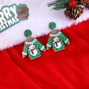 Detailed view of green Christmas sweater earrings with snowman motif on festive background