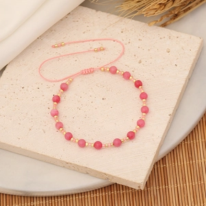 Detail of pink beaded bracelet with gold accents and adjustable drawstring cord