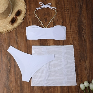 Dettaglio del bikini bianco con conchiglie dorate, perle e pareo da spiaggia in mesh