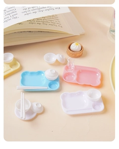 Detailed close-up of miniature dollhouse kitchen tableware set in pastel colors