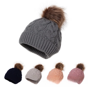 Detail of five colors of chunky knit toddler hats with large faux fur pom-poms