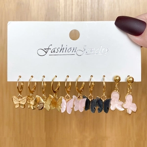 Set of 6 pairs of gold butterfly earrings with resin and metal charms on a white card