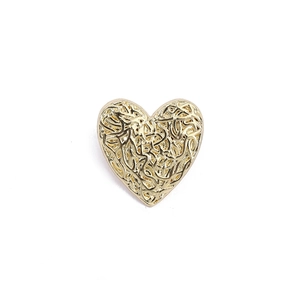 Detail view of heart-shaped golden alloy brooch with intricate hollow filigree pattern