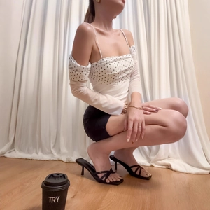 Polka dot off-shoulder long sleeve top and black mini skirt worn by a model in a natural setting