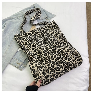Detailed view of the leopard print canvas tote bag on a bed next to a denim jacket