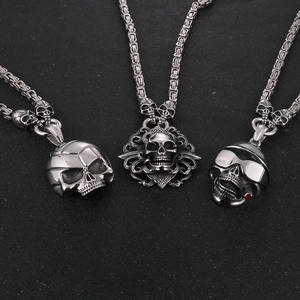 Three punk skull pendants with silver stainless steel chains on black background