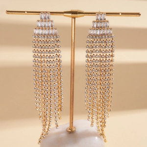 Detail view of long gold tassel earrings with clear cubic zirconia on a jewelry stand