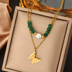 Detail of double-layer gold necklace with butterfly pendant and pearl beads in a jewelry box