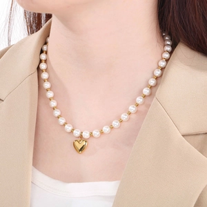 Detailed view of beaded pearl necklace with a gold heart pendant on a female model