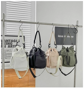 Multiple nylon bucket bags in four colors hanging on a rack for fashion display
