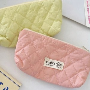Vue détaillée de trousses à maquillage matelassées en jaune et rose pastel avec patch