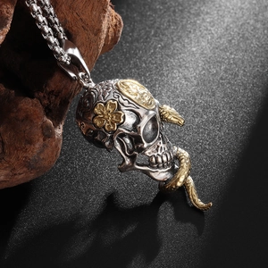 Macro view of silver skull pendant with golden snake and flower carving detail