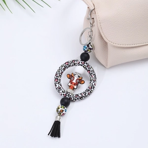 Detail of cartoon cow keychain with leopard print silicone ring and black tassel decor