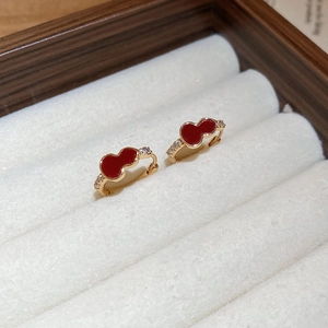 Detailed macro view of gold-plated red gourd earrings with white zircon accents