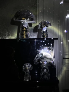 Detailed view of silver mirror mushroom disco balls reflecting light on a piano