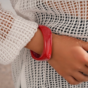 Detailed view of an irregular red resin cuff bracelet on a female wrist model