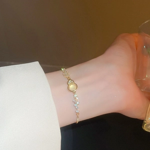 Close-up of a gold gourd bracelet with crystals on a woman's wrist in elegant setting