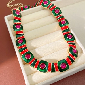 Detail showing vintage necklace with green enamel panels and red gemstone accents in a box