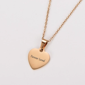 Macro shot of rose gold heart pendant with Forever Loved engraving and polished finish