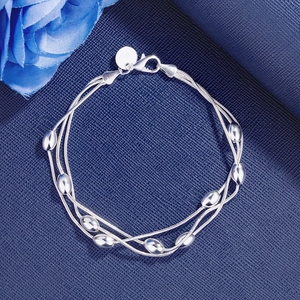 Elegant 925 sterling silver plated triple-strand bead bracelet with oval charms on blue surface