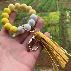 Detail of a silicone bead keychain featuring yellow beads and a faux leather tassel