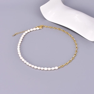 Detail view of asymmetric necklace featuring freshwater pearls and golden pig nose chain links