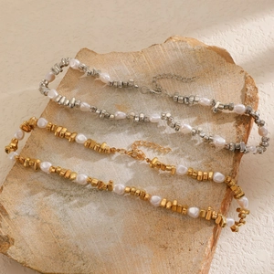 Gros plan de colliers en perles baroques avec perles carrées dorées et argentées