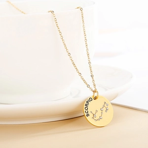 Detailed macro shot of Scorpio gold zodiac necklace draped on white ceramic cup