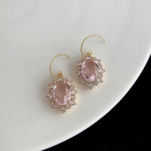 Détail de boucles d'oreilles en pierres roses avec placage or et zircons scintillants