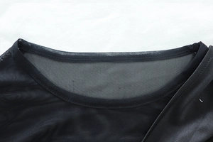 Detail of the crew neck and semi-transparent black mesh fabric on long-sleeved dress