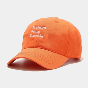 Detailed embroidery of white letters on an orange cotton baseball cap with curved brim