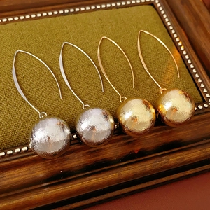 Détail de boucles d'oreilles boules texturées dorées et argentées sur velours vert