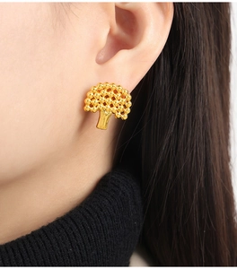 Detailed close-up of tree-shaped gold plated stud earrings with textured bead design
