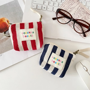 Close-up of canvas striped cosmetic bags with colorful embroidery on a desktop background