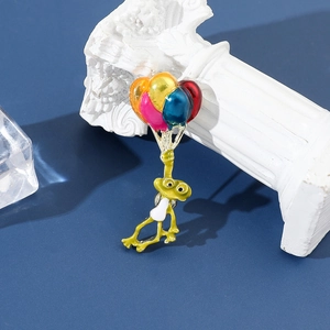Détail de la broche grenouille en émail vert avec ballons colorés sur fond bleu