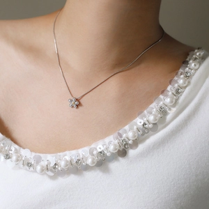 Close-up of a silver daisy flower pendant necklace worn on a model's collarbone
