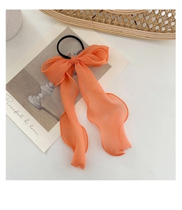 Detail view of a large coral lace ribbon bow hair tie with delicate chiffon texture