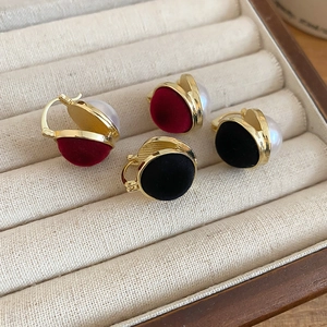 Detail of vintage velvet pearl earrings in red and black colors with gold metal frames