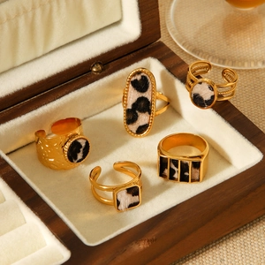 Close-up of assorted gold leopard print stainless steel rings in a wooden jewelry box