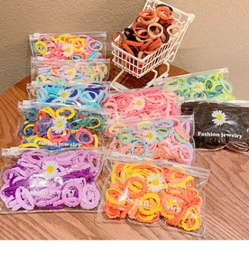 Élastiques à cheveux colorés en sachets sur bois avec un petit chariot de décoration