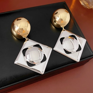 Close-up of stylish gold stud and silver hollow diamond earring on black leather case