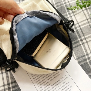 Minimalist canvas crossbody bag in beige showing interior capacity for smartphone