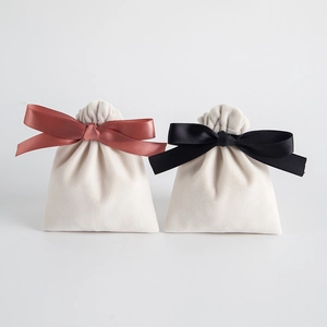 Detail of cream velvet jewelry pouch featuring elegant satin bow closure in red and black